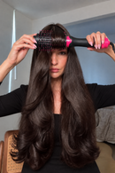 Foto da modelo escovando o cabelo com a escova secadora, de blusa preta, no mesmo estilo